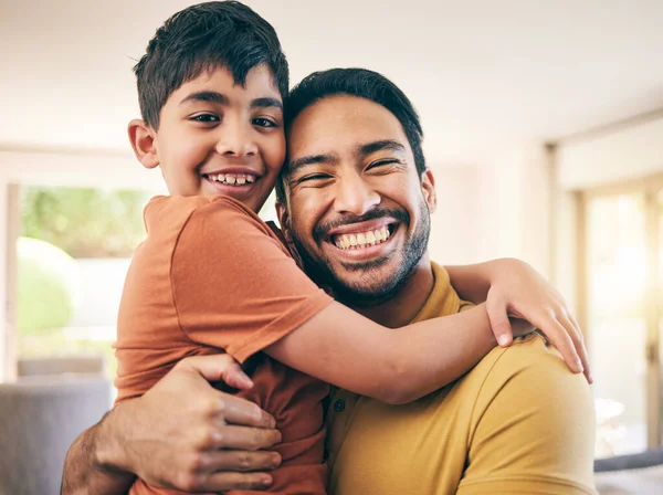 Happy, portrait and father hugging his child in the living room of a modern house for bonding. Smile, love and excited young dad embracing his boy kid from Colombia in the lounge of a family home