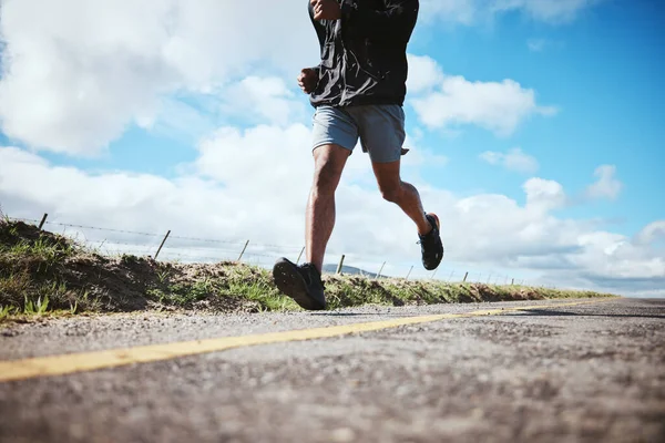 レースで心臓トレーニングのために青い空と雲の上の道で男と一緒に走る脚 フィットネス トレーニングやマラソンのための男性ランナーやアスリートアウトドアでの運動 — ストック写真