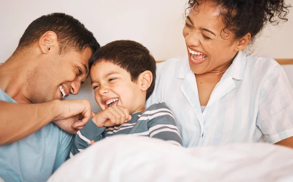 Happy, tickle and smile with family in bedroom for playful, morning and love. Care, support and wake up with parents and boy child laughing in bed at home for weekend, positive and relax together.