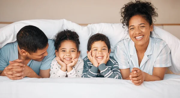 Smile, love and portrait with family in bedroom for playful, morning and happy. Care, support and wake up with parents and face of children laughing in bed at home for weekend and relax together.