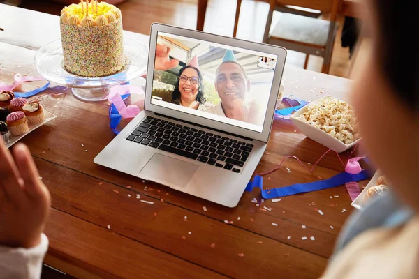 Birthday cake, video call and laptop on table with people online to celebrate on virtual chat. Couple talking to family with internet connection, communication and technology at home for celebration.