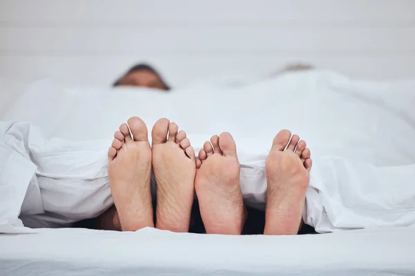 Couple, bed and feet with blanket in sleeping, peace and morning rest together on weekend at home. Barefoot people, asleep and comfort in bonding, care or love under duvet in bedroom at the house.