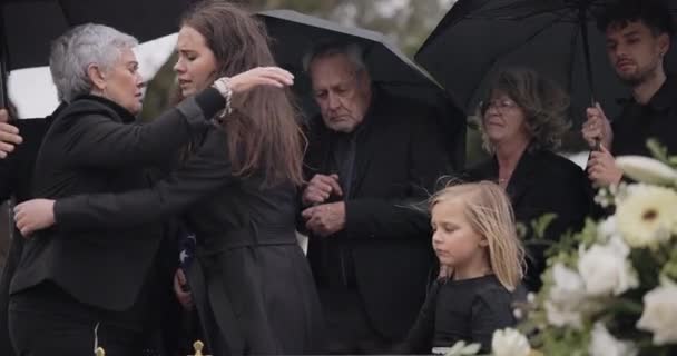 丧葬时 哭着的家人和人们拥抱在悲痛的支持下 哀悼抑郁症和在感情丧葬事件中死亡 在棺材仪式上 妈妈和一群人与寡妇拥抱年长的妈妈 — 图库视频影像