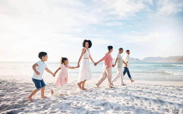 Big family, holding hands and walking at the beach for travel, vacation and adventure in nature. Love, freedom and children with parents and grandparent at sea for fun, journey and bond ocean holiday.