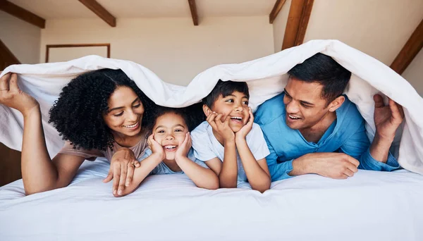 ベッドの上の笑顔 家族は リラックスしたり 結合したり 自宅で一緒に休んだりするための毛布を持っています 現代の家の部屋でコロンビアから両親と幸せ 興奮し 若い子供たち — ストック写真