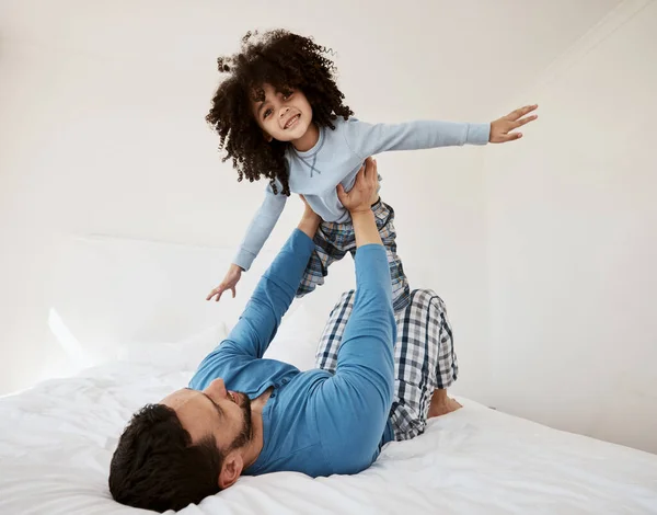 Playing, portrait and a child with a father in the bedroom for flying, happiness and bonding. Smile, house and a dad with a girl kid on the bed in the morning together for childhood and goofy.
