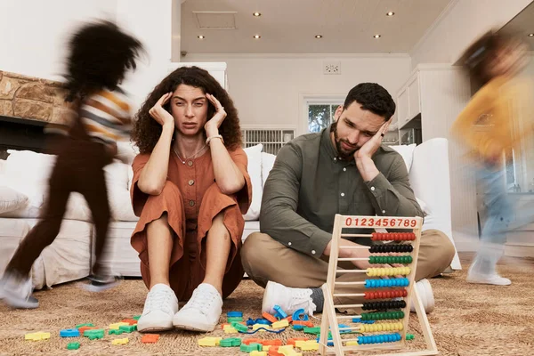 Parents, floor and stress with children running, toys or motion blur for speed, game or overwhelmed in home. Mother, dad and kids on carpet, living room and family house in chaos, anxiety or burnout.