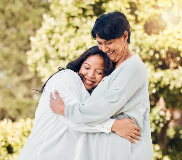Mature woman, daughter and hug in garden with love on mothers day or women bonding with care for mom in retirement. Happy, family and embrace outdoor, backyard or together on holiday or vacation.