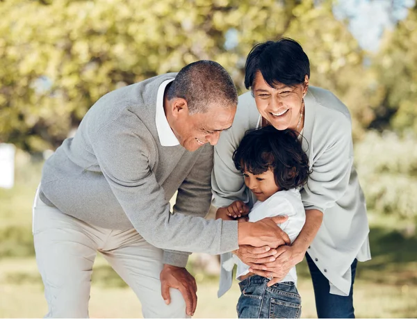Happy, hug and grandparents with child in park for playing, love and support. Care, smile and freedom with family and embrace on nature path for peace, summer vacation and happiness together.