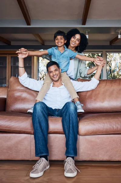 Smile, airplane and portrait with family on sofa for happy, bonding or peace on holiday. Love, care and playful with parents and child in living room at home for vacation, cuddle and embrace together.