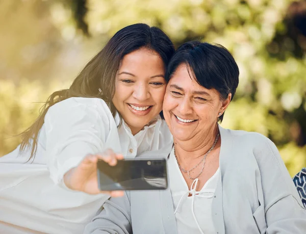 Woman, mature mother or selfie in garden on mothers day taking photograph for memory, support or love. Social media, pictures or mom with a happy daughter in outdoor park together on holiday vacation.