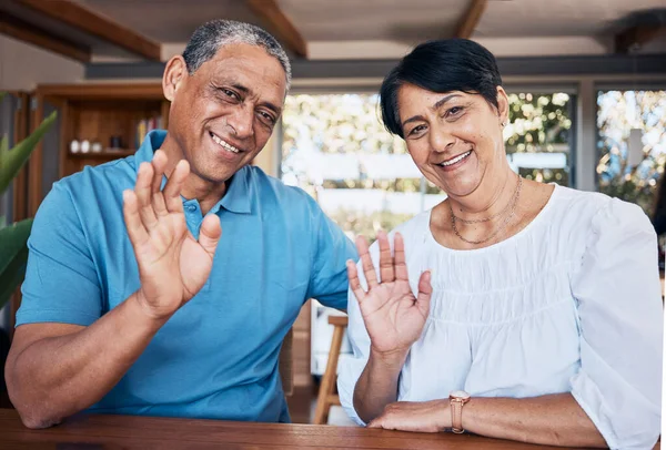 Video call, wave and portrait of senior couple with communication in the dining room at home. Happy, smile and elderly man and woman in retirement greeting for an online virtual conversation together.