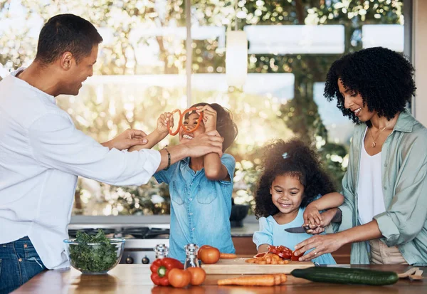 Cooking, health and funny with family in kitchen for learning, food and nutrition. Wellness, support and vegetable with parents and children at home for meal prep, support and dinner together.