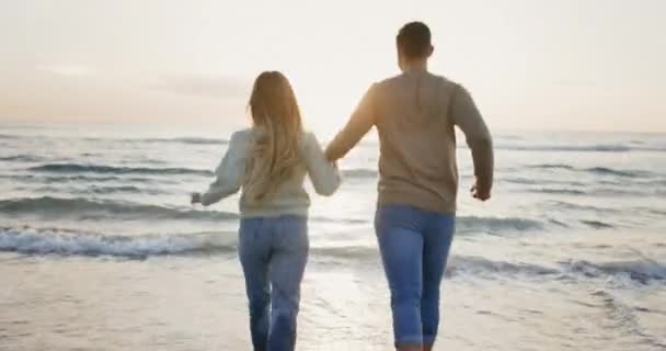 情侣们 奔向大海 牵着手 在海滩上玩耍 在户外嬉笑 自由自在 在波涛中玩耍 浪漫的约会 日落时的人们 在健康的关系中充满爱心和关心 — 图库视频影像