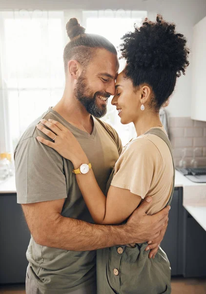 Interracial couple, hug and forehead touch in kitchen, love and bonding with happiness while at home. Trust, support and commitment, affection and embrace with people in a healthy relationship.