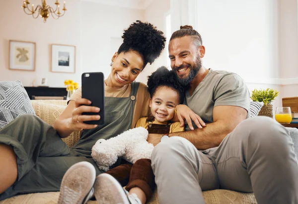 Interracial parents, child and selfie on sofa, smile and hug for love, bonding and memory on web blog. Mom, dad and kid for photography, profile picture and happy for social media app in family house.