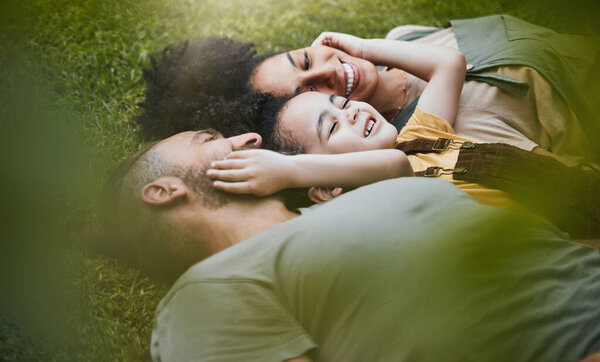 Care, happy and a family lying on the grass in nature for bonding, laughing and comfort. Love, smile and an interracial, father, mother and boy kid in a garden or backyard with an embrace together.