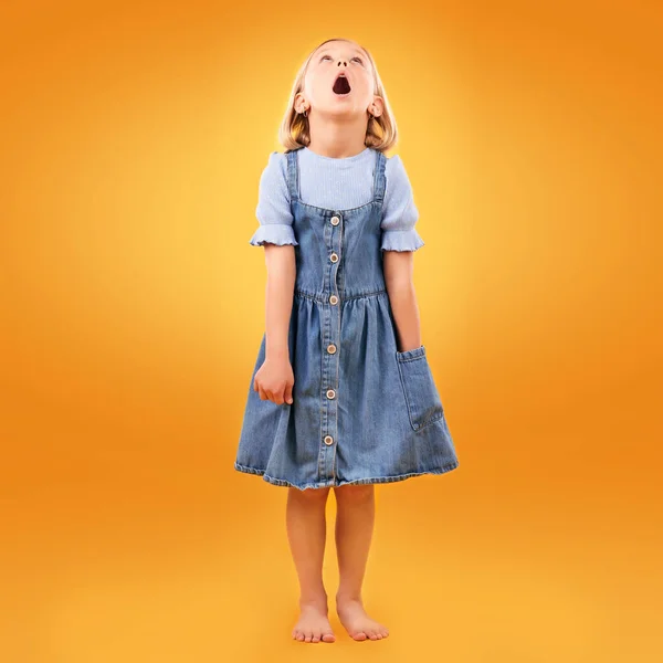 stock image Fashion, wow and girl child in studio for news, omg or coming soon promotion on orange background. Looking up, surprise and kid shocked by choice, sale or discount, announcement or prize giveaway.