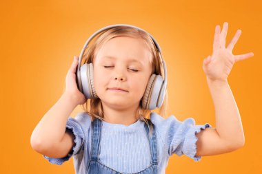 Çocuk, kulaklık ve dans özgürlük için stüdyoda müzik, multimedya aboneliği veya turuncu arka planda çocuk podcast 'i. Mutlu genç kız radyoda müzik dinliyor, müzik dinliyor ya da şarkı dinliyor..