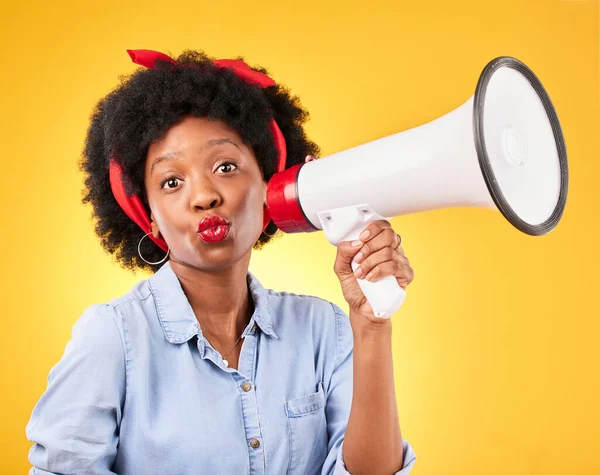 Woman, megaphone and portrait for announcement, broadcast or fashion news on yellow background. Young gen z or african person with kiss face emoji and sale, voice or discount communication in studio.