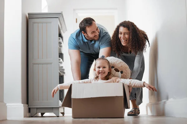 Child playing, father or mother pushing box in new house in a race or game for bond, love or happiness. Dad, playful mom or excited girl kid in cardboard with support, smile or parents in family home.