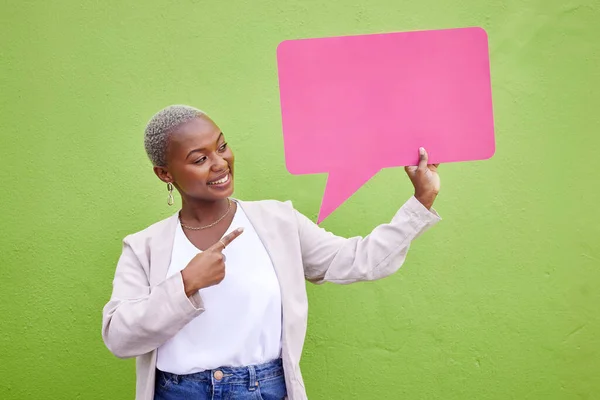 Black woman, speech bubble and thinking for pointing, space or mockup with opinion by green wall background. African girl, billboard and paper poster for voice, vote and social network for feedback.