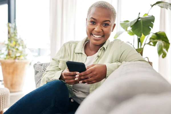 Woman, portrait and smile with phone on couch for social media post, search tech contact or subscription to mobile games. Happy african person, smartphone user and download digital multimedia at home.