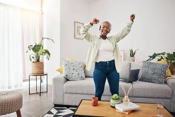 Dance, black woman and listening to music in the living room for freedom, the radio or an audio. Happy, streaming or African girl with headphones for a podcast, playlist or enjoying a song in a house.