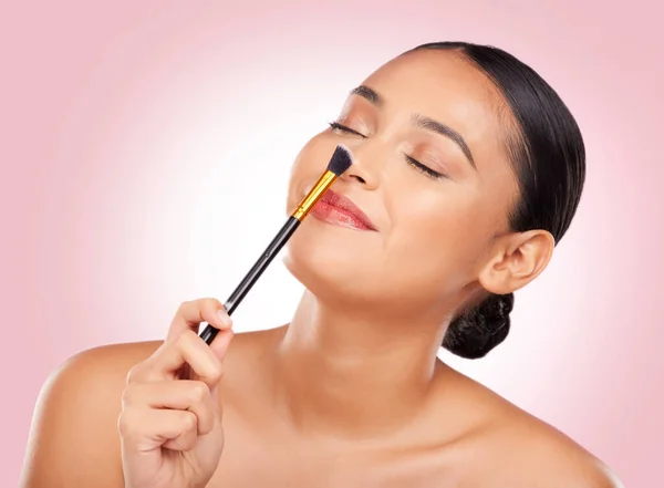 Woman, makeup and brush nose in studio for beauty, skincare and face application on pink background. Happy model, dermatology and cosmetics tools for facial contour, powder and aesthetic foundation.