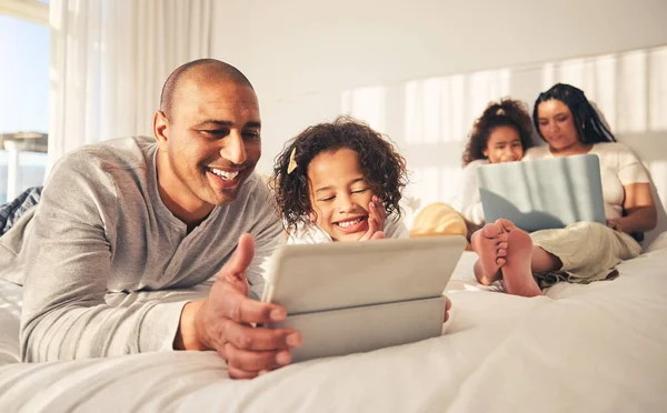 Relax, family and technology in the bedroom for movies, cartoon or education on the internet. Happy, together and parents with girl kids and a laptop and tablet for streaming a show, film or games.