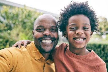 Portre, baba ve çocuk birlikte tatilde rahatlamak için mutlu bir aile olarak özçekim yaparlar. Gülümse, yüzler ya da Afrikalı baba heyecanlı bir çocuk ya da çocukla parkta fotoğraf çekiyor..