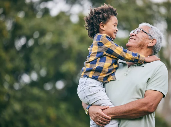 Hug, love or grandpa with child in nature for bonding, travel or adventure together in retirement. Eye contact, smile or kid with grandfather in park, forest or woods on holiday vacation with care.