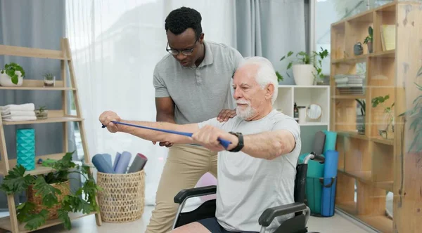 Senior man with disability, physiotherapist and stretching band for muscle rehabilitation, chiropractor service or help. Physical therapy, medical support or patient in wheelchair at recovery clinic.