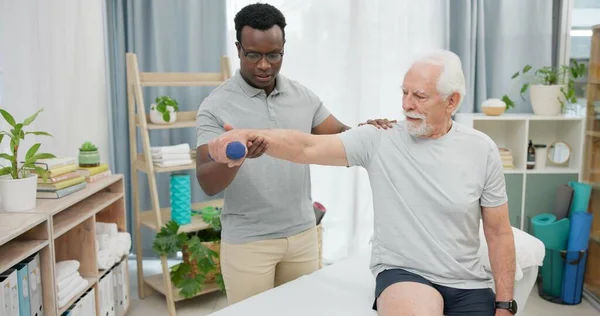 Arm physiotherapy, dumbbell or person with old man for support, recovery in motion training. Physical therapy, rehabilitation or African physiotherapist helping elderly patient with mobility exercise.
