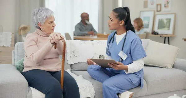 Healthcare, consultation and nurse with senior woman in the living room of the retirement home. Medical, checkup and female caregiver speaking to elderly patient with walking cane in nursing facility.