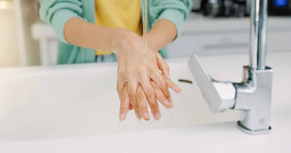 Washing hands, woman cleanse and kitchen sink of a female with soap for cleaning and wellness. Home, safety and virus protection of a person with healthcare in a house for skincare and grooming.