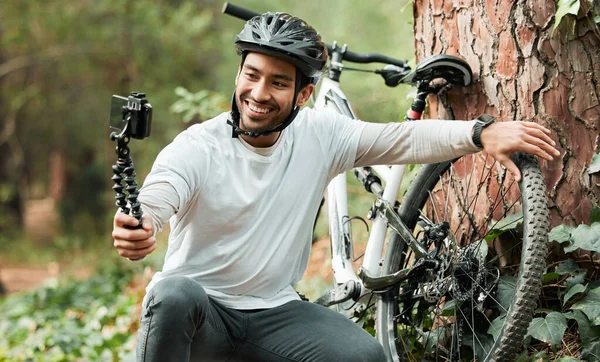 Man, selfie and bike by trees, forest and smile for training, health and outdoor adventure with web blog. Influencer guy, cycling and bicycle with live stream, profile picture and social media post.