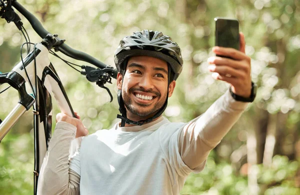 Man, bicycle and forest for selfie, nature or smile for wellness, training or blog on adventure. Influencer guy, cycling and mountain bike for profile picture, memory or live stream on social network.