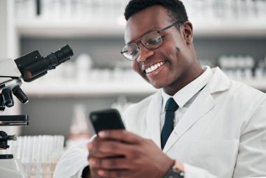 İnternet, e-posta ya da web sitesi laboratuarında tıbbi bilimler ve bir telefon. Akıllı telefon daktilo tıp araştırması, sosyal medya veya ağ veritabanına sahip mutlu Afrikalı bilim adamı.
