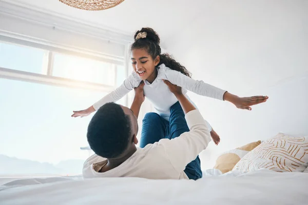 Happy, airplane and father with girl child on a bed for bond, trust or support in their home together. Flying, family time and parent with kid in a bedroom for games, love or fun with weekend freedom.