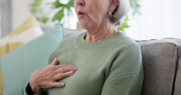 家のリビングルームのソファーに心臓病を患っているハンド シニアの女性 退職中に家で一人で高齢者と健康 心停止 — ストック動画