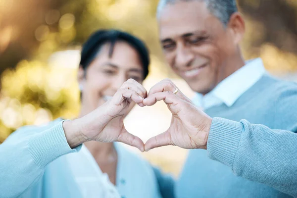 Hands, heart and emoji with a senior couple outdoor in celebration of their love or anniversary together. Hope, trust or peace with an elderly man and woman closeup for freedom or romance in summer.