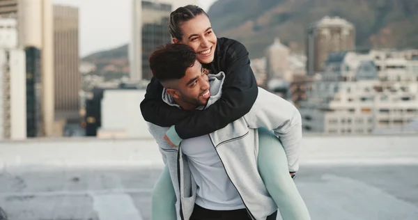 Fitness, piggyback and couple in a city with love, hug and bind in training or cardio routine. Sports, love and man with woman outdoor for workout, challenge or exercise, happy and embrace in town.