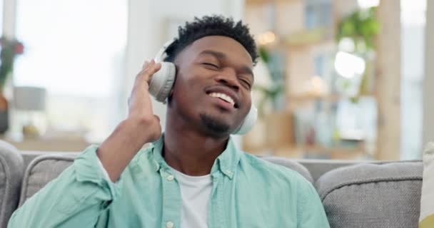 耳机和音乐与平板在家里音频 收音机和放松与播客在沙发上 快乐的非洲小伙子 听数字多媒体应用 流声或听歌曲 — 图库视频影像