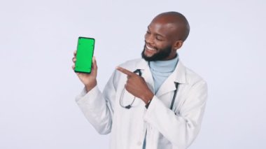 Yeşil ekran, stüdyoda doktor ve tıbbi reklamlar için model yeri var. Gülümse, takip işaretleri ve beyaz arka planda cep telefonu olan siyah bir sağlık görevlisinin yüzü.