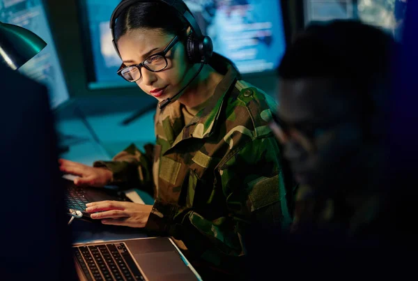 Military control room team, headset and woman with computer and tech for communication. Security, global surveillance info and soldier thinking in army office at government cyber data command center