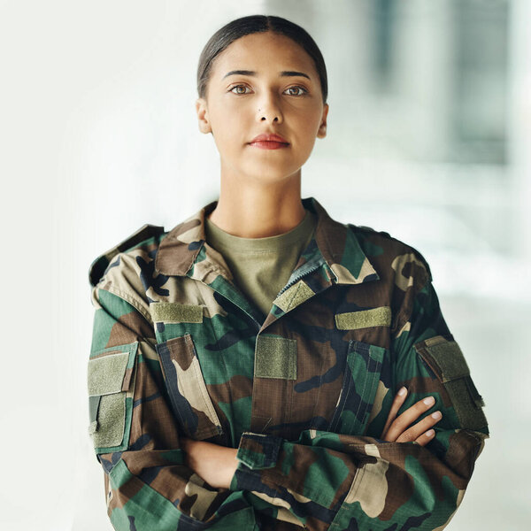 Confident soldier portrait, woman and arms crossed in army building, pride and professional hero service. Military career, security and courage, proud girl in camouflage uniform at government agency