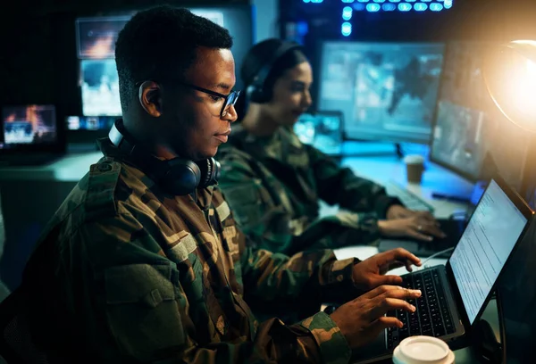 Military control room, computer and soldier at desk, typing code and tech for communication army office. Security, global surveillance and black man at laptop in government cyber data command center