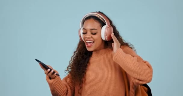 インターネット バックパック 歌のためのスタジオでヘッドフォンを持つダンス 学生の女性 スマートフォン ストリーミング またはブルーバックグラウンドでリラックスする音楽を聴くGen Zの人 — ストック動画