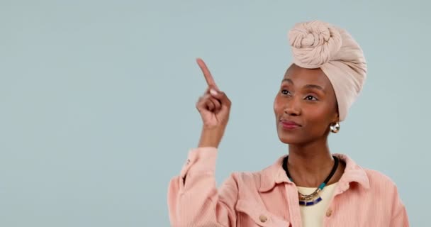 アフリカの女性 肖像画 アナウンス 笑顔のためのスタジオで指を指します プレゼンテーションとバナーのための青い背景にターバンと手のジェスチャーを持つ黒人女性の顔 — ストック動画